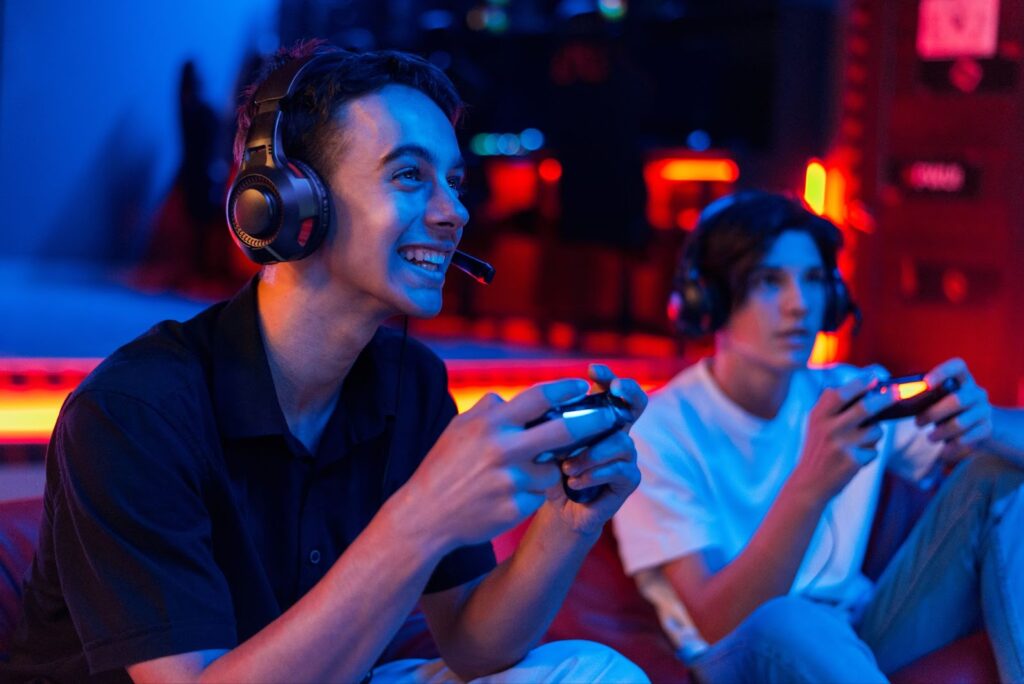 Two teen friends in headphones are playing a game console